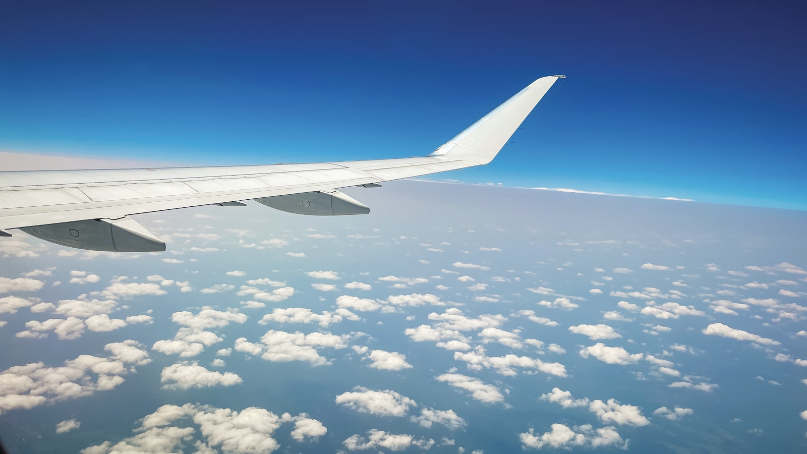 Airplane wing over clouds and blue sky