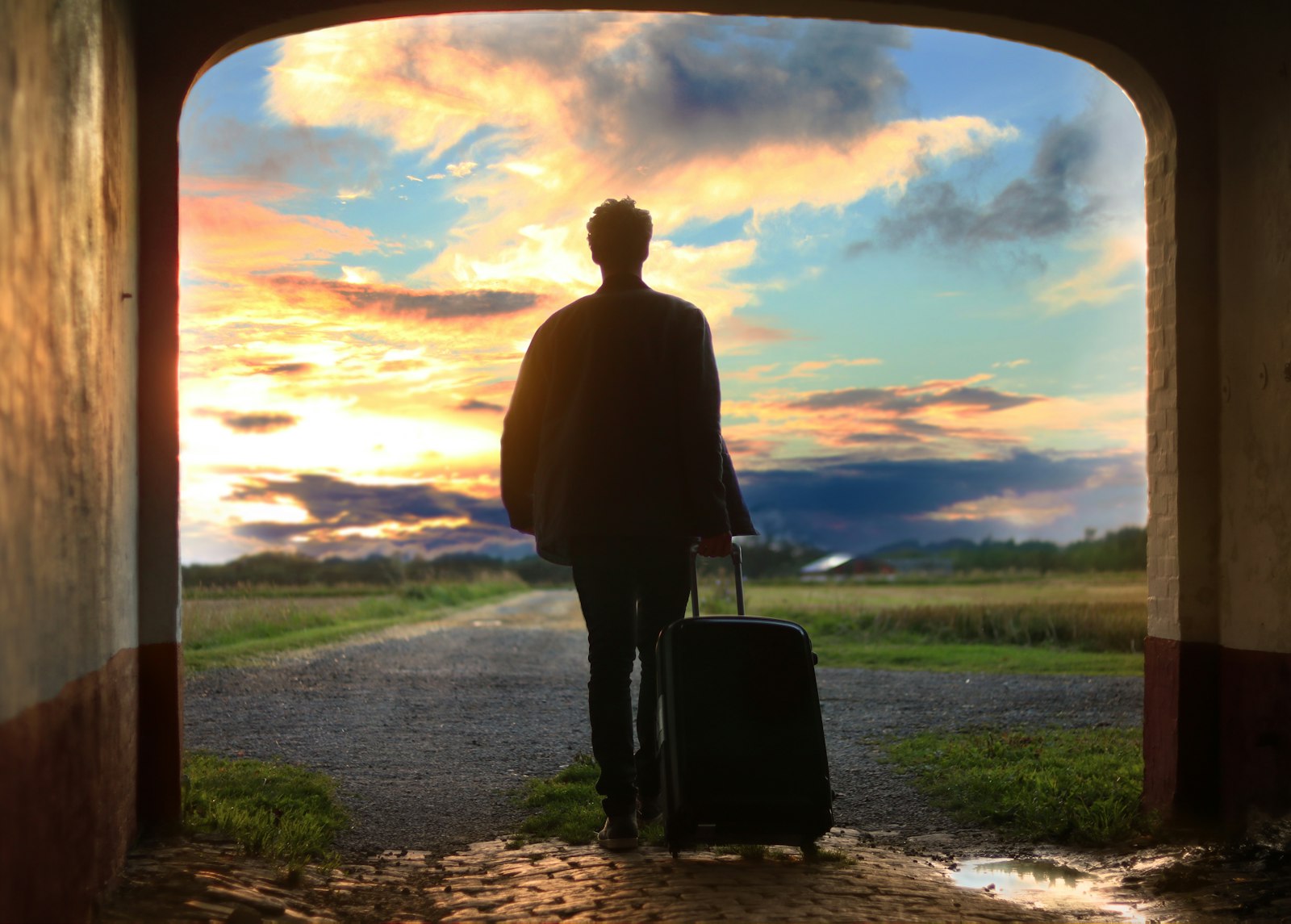 Traveler walking with suitcase toward a sunset horizon
